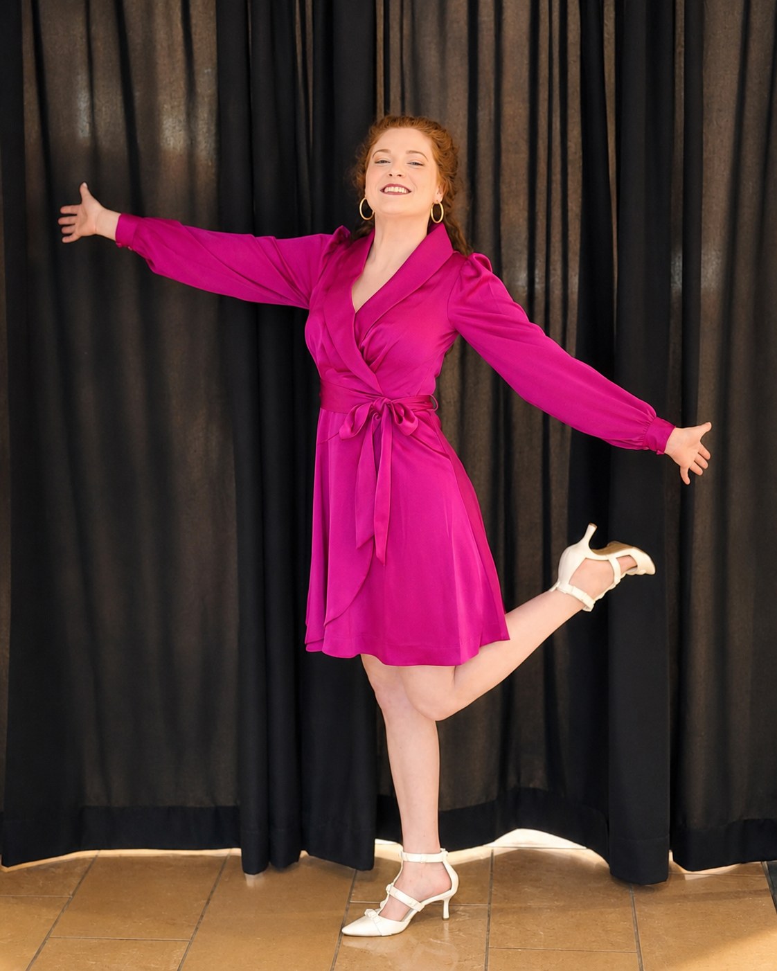 Kayla smiling in a bright pink dress with her arms open