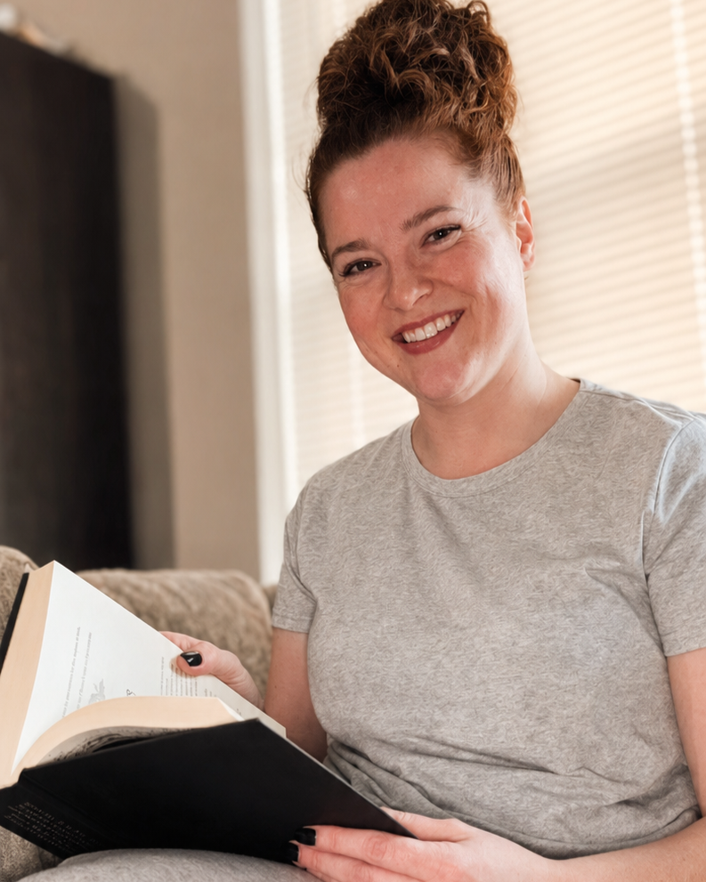 Kayla relaxing on the couch with an open book